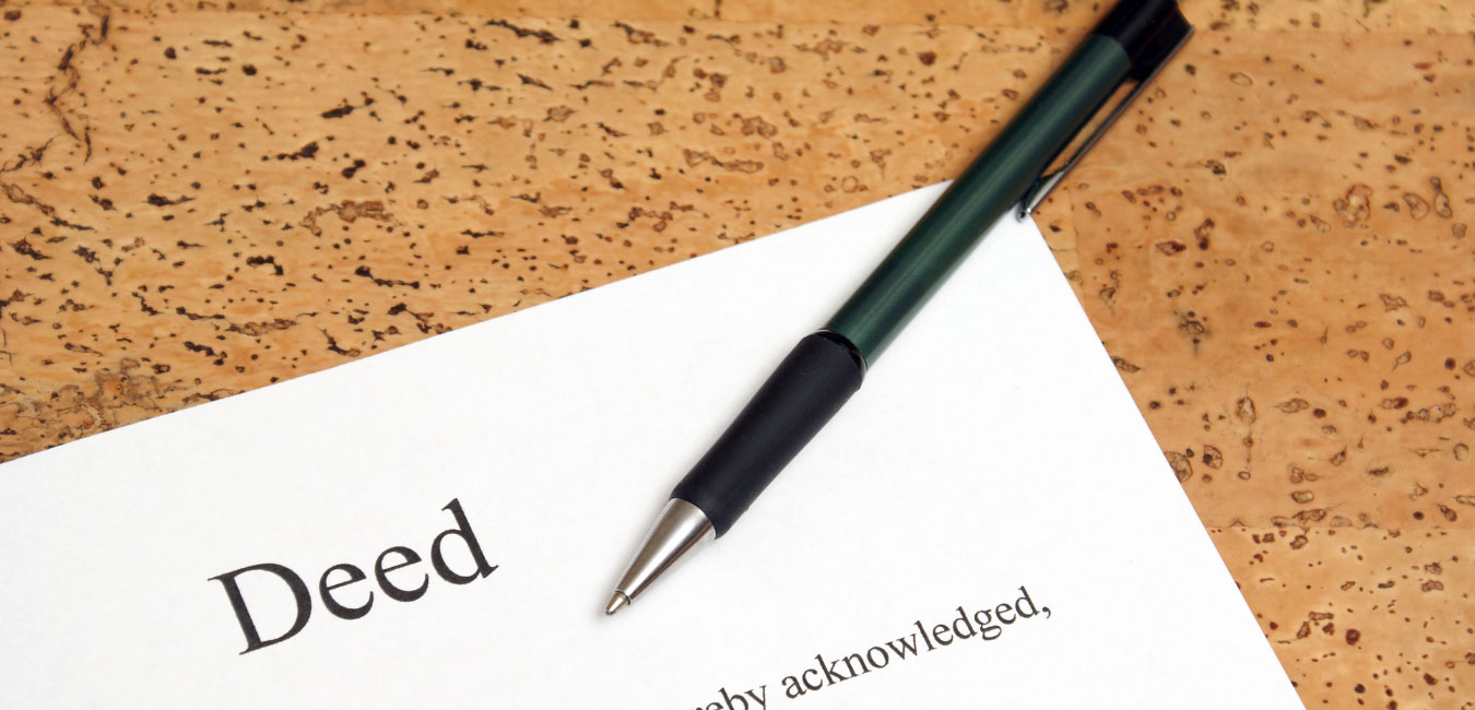 unmarried partners should ensure their Deed paperwork is in alignment with their wishes - with pen on brown cork looking countertop