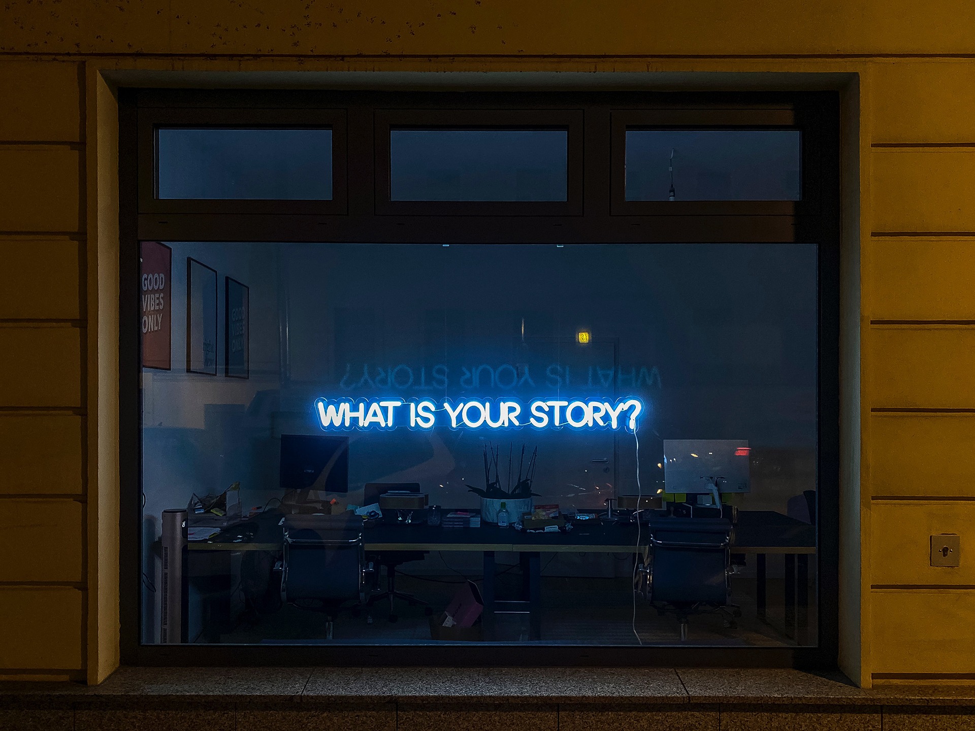 window with a neon sign that says what is your story